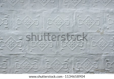 The white wall of the old building is lined with unusual decorative ceramic tiles