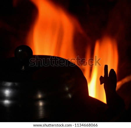 Isolated dark metallic tea kettles with fire background unique photo