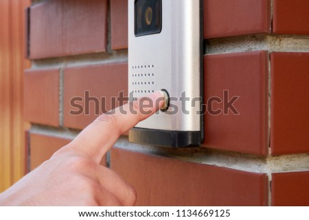 The female hand presses a button doorbell with camera and intercom Royalty-Free Stock Photo #1134669125