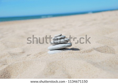 Stack of stones on sandy beach. Stone pyramid in balance, blue sea, blue sky.