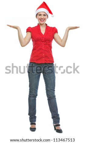 Happy young woman in Christmas hat presenting something on empty palms