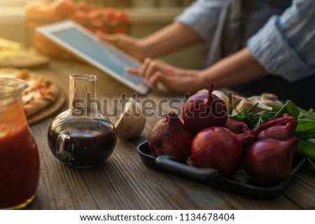The young woman looking recipe in a tablet computer in kitchen. Healthy food. Healthy lifestyle. Cooking at home. Cooking according to recipe on tablet screen. Technology concept. Toned image. Royalty-Free Stock Photo #1134678404