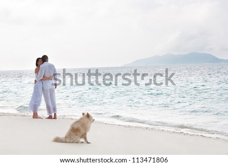 Picture of romantic young couple on the sea shore with dog