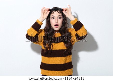 Beautiful young woman in sweater and glasses on white background