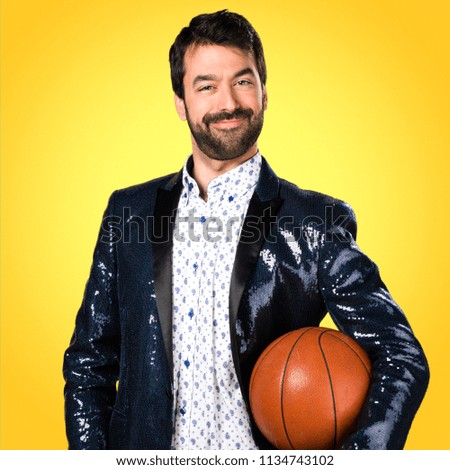 Man with jacket holding a basket ball on colorful background