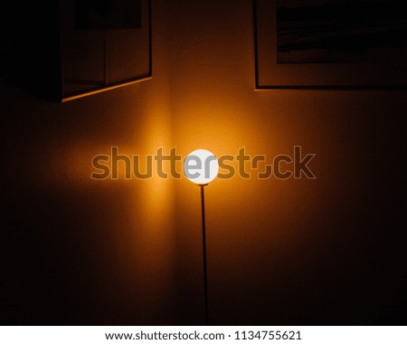 A lamp shines besides picture frames in the hallway of a home