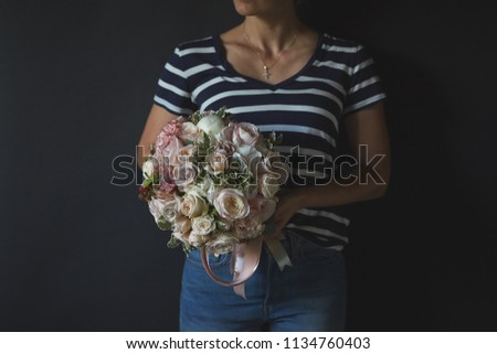 gift bouquet in the hands of a girl on a black background