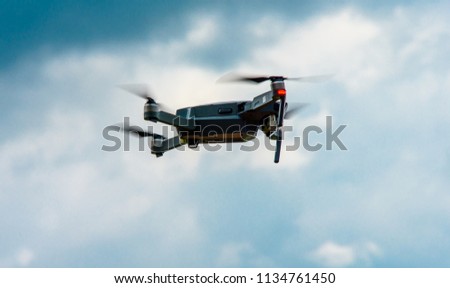 an unmanned helicopter flying with a digital camera. Demon with a digital camera of high resolution. The flying camera takes photos and video. A drone with a professional camera against a blue sky wit
