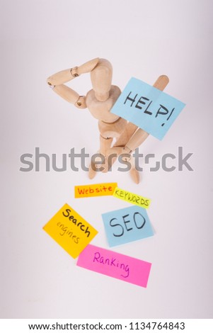 Wood jointed doll figure holding Help sign sticky notes with SEO ranking website keywords 