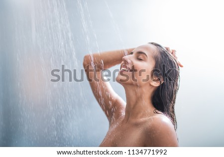 Side view happy woman washes body and hair under stream of hot water Royalty-Free Stock Photo #1134771992