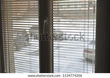 view from the window to the snow through the blinds