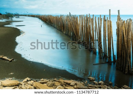 Long exposure seascape bamboo wall to protect the shore from the surf of the sea waves.Thailand