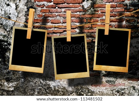 Old picture frame hanging on clothesline on grunge wall.