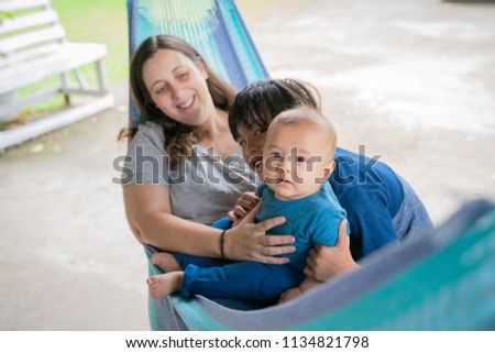 The little boy and mother are sitting at the hammock, both are happy