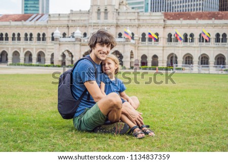 Dad and son on background of Merdeka square and Sultan Abdul Samad Building. Traveling with children concept.