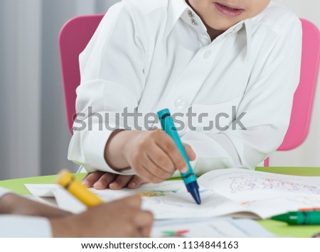 Kids drawing with colored crayons on paper at a table