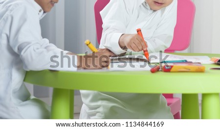 Kids drawing with colored crayons on paper at a table