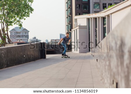 Young handsome man with beard riding longboard on the street.