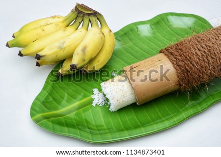 Popular South Indian breakfast Puttu or Pittu made of steamed rice flour and grated coconut  in the bamboo mould with banana Kerala, India. Sri lankan food