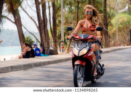 cheerful girl, on a scooter, driving, while driving on the street, in the afternoon