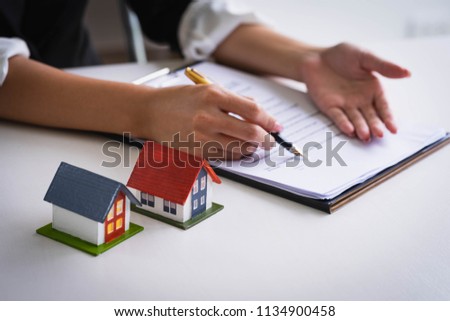 Estate agent use the pen pointing on document showing where to sign. Signing a paper document for buying house.Real estate, home loan and insurance concept Royalty-Free Stock Photo #1134900458