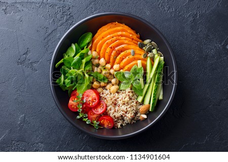 Healthy vegetarian salad. Roasted pumpkin, quinoa, tomatoes, green salad. Buddha bowl. Slate background. Top view. Royalty-Free Stock Photo #1134901604