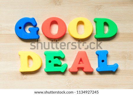 Color plastic alphabet in word good deal on wood background