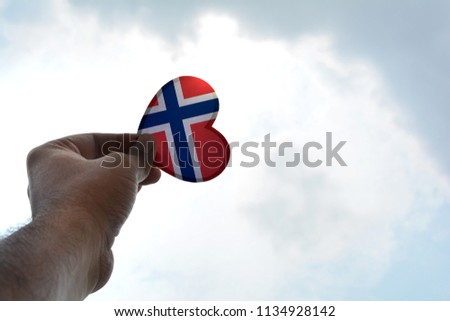 Hand holds a heart Shape Norway flag
