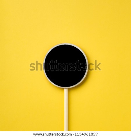 Wooden information label sign with circle and black empty place for text, Blank blackboard label isolated on yellow  background, Top view and copy space.