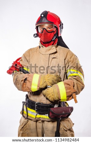 Anonymous firefighter wearing helmet and protective suit holding ax and looking at camera on white. 