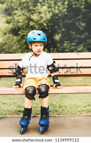 Boy sitting roller skates at outdoor park summer day
