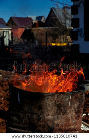 Burning garbage in rusty iron barrel on the countryside area