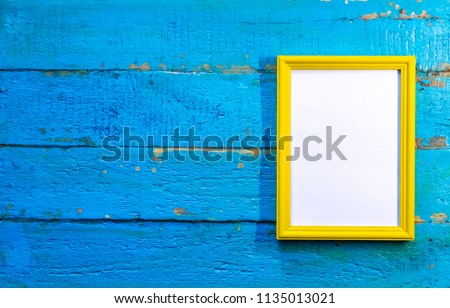 frame for photographs and images of yellow color with a blank white background inside on a blue textured wooden wall