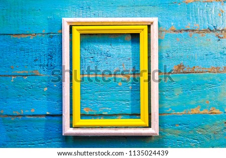 yellow frame inside a white frame for photos and images with a blank space inside on a blue textured wooden wall