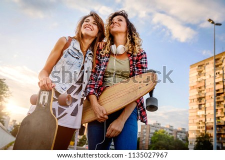 Smiling skateboarding girls sitting in the street hanging out