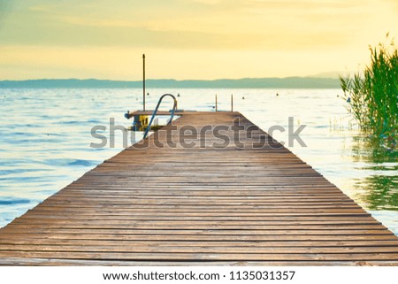 Long wooden pier at Lake Garda in Italy at sunset / slightley blurred picture with nice bokeh