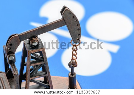 Petroleum, petrodollar and crude oil concept : Oil pump jack and flag of OPEC or Organization of Oil Exporting Countries, depicts the investment in the development or production of global oil industry
