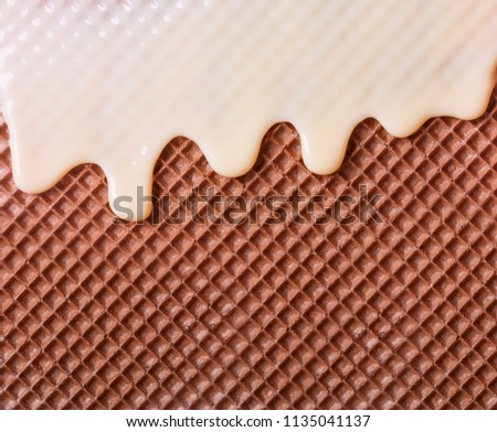 White hot chocolate on the wafer. Waffle covered with condensed milk close-up. White hot chocolate spreads on the wafer.