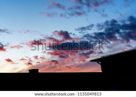 Stunning beautiful, colorful sunset in the sky over the silhouette of the house.