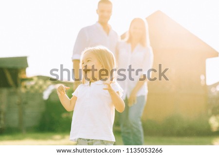 selective focus of happy little kid with parents behind on backyard