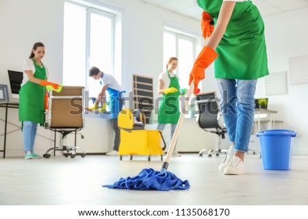 Team of professional janitors in uniform cleaning office Royalty-Free Stock Photo #1135068170