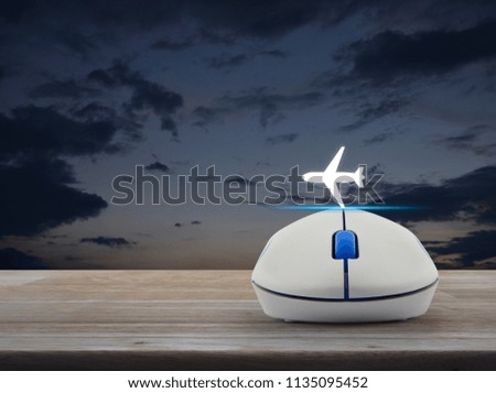 Airplane icon with wireless computer mouse on wooden table over sunset sky, Business transportation concept