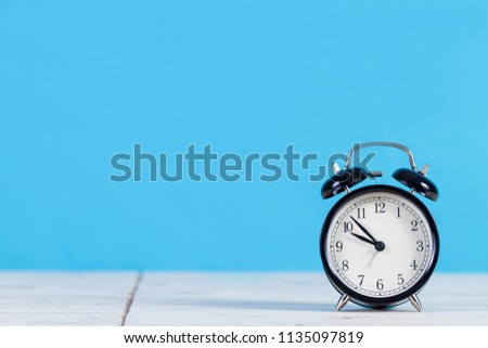 A Black Retro alarm clock on wooden board with blue background