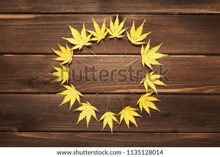 Autumn frame for your idea and text. In autumn, yellow dry leaves, circled to the center on an old brown wooden board. Autumn model. Top view