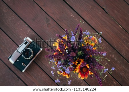 Vintage retro camera and spring flowers branches on rustic wooden table. top view. flatlay