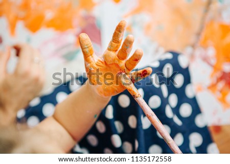 Selective focus on dirty  children hands with orange color on them .Finger paint.