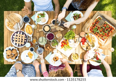 Top view of a wooden table with pizza, cherry pie, fruit, vegetables and pancakes during a vegetarian outdoor party