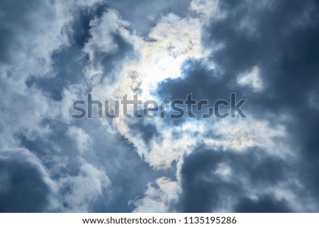 Dark clouds on blue sky with sun rays