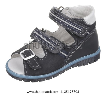 Side upper view of black, blue and white suede and leather boy sandal with slits and slots, rubber sole, clasp and two velcros, isolated on white