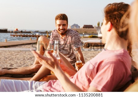 Picture of friends have a rest outdoors on the beach drinking beer.